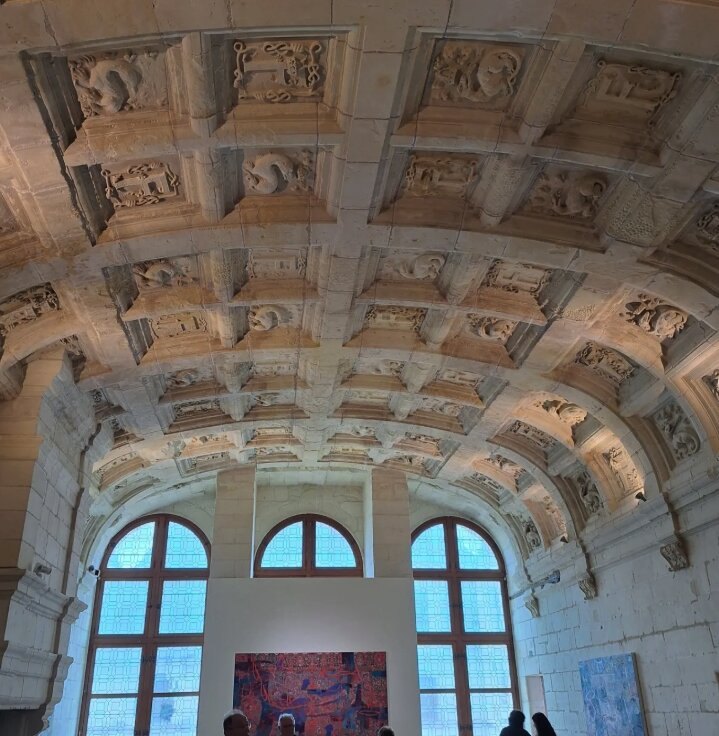 The carved coffered vault of a second-floor room, tall windows at the far end